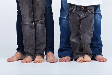Family legs in jeans portrait - barefoot on white background