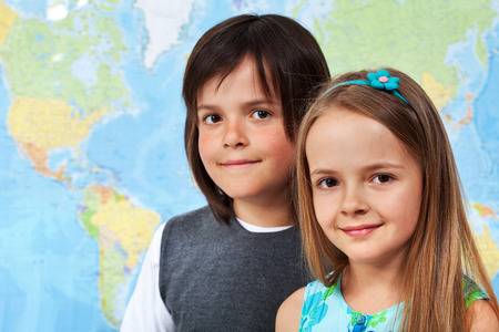 Children in geography class - portrait in front of large wall map, with copy spaceの写真素材
