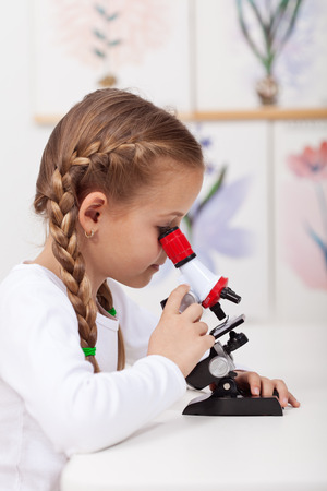 Little student study plants in biology science class - looking at samples on microscopeの写真素材