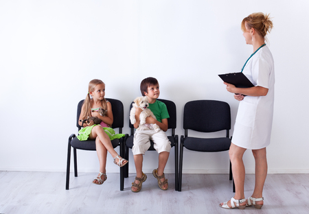 Kids taking their pets to the veterinary doctor - sitting and holding their furry friendsの写真素材
