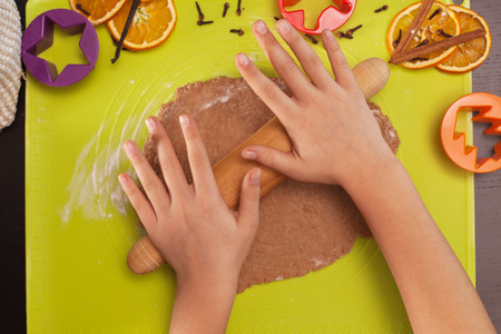 Stretching the christmas cookies dough - child hands with rolling pin, top viewの写真素材