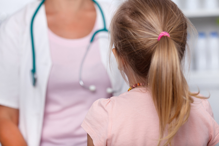 Little girl being examined at the doctor - facing the healthcare professional, shallow depth of fieldの写真素材