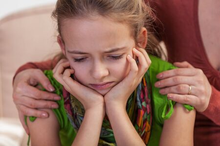 Woman hands holding the shoulders of desperate young girl with sad expression - close up