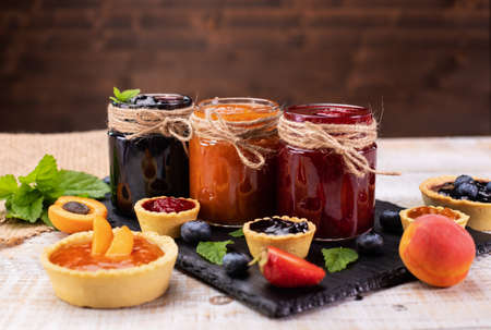 Delicious summer fruits jam - various berries and assorted jams on wooden tableの写真素材