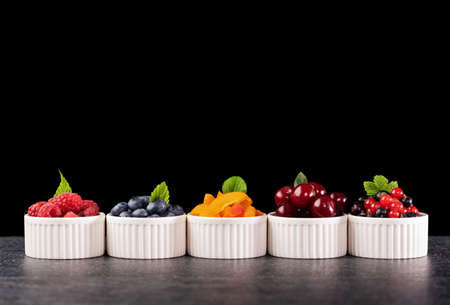 Fresh summer fruits in small recipients - with copy space. Colorful healthy snacks. Raspberry,...