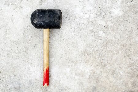 The black hammer with a wooden red handle lies on a gray grunge concrete backgroundの写真素材