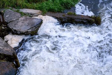 Dynamic river water splashing and foaming over rocks, creating a powerful natural texture and motion. Ideal for nature or environmental backgroundsの写真素材