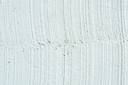 Close-up grunge wall with white cracked plaster and rough vertical texture. Perfect for backgrounds, building materials, renovation projects and creative design.の写真素材