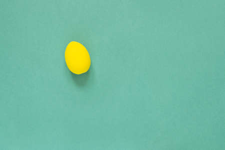 One colored yellow painted egg on green background Easter card with empty space for text. Happy Easterの写真素材