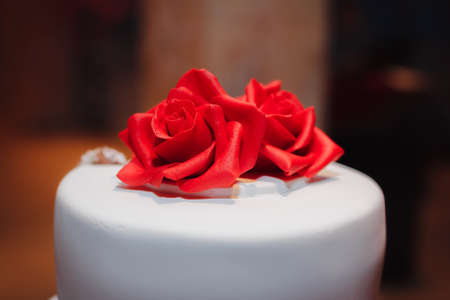 gorgeous white cake decorated with red flowers, roses, ribbons and bow, weddingの写真素材