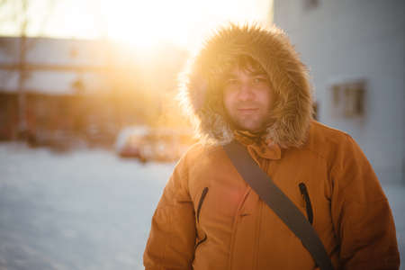 Portrait of the charming man who is smiling and talking on the phone in the winter cold day at sunset, dawn. Winterの写真素材