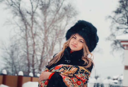 beautiful girl in winter clothes, coat and hat, posing near the church in the winter, in the snowの写真素材
