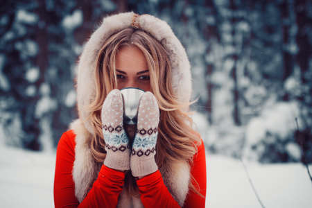 beautiful girl is drinking a hot drink from a cup in the winter in nature, tea, coffeeの写真素材