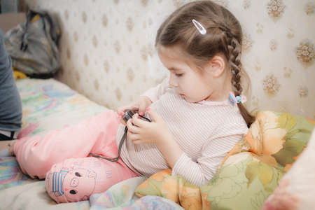 little girl lying on the couch and looking at the pictures in the camera at homeの写真素材