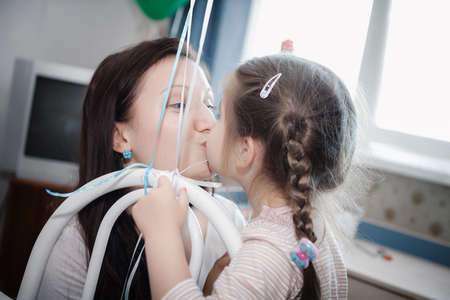 Mom kisses daughter, when she is playing with balls at homeの写真素材