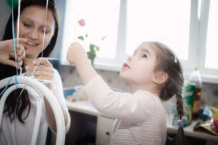 little girl reaching for balls, they are tied to a chairの写真素材