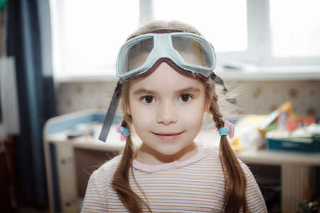 little girl playing at home with glasses of pilot, happyの写真素材