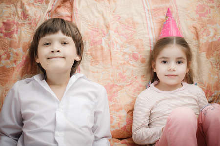 brother and sister sitting at home whiteの写真素材