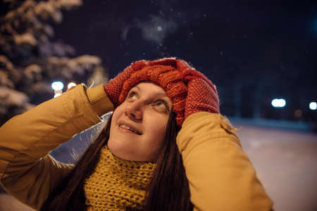 the girl's portrait in the winter against the background of the evening city which to something is surprised. in the light of city lamps.の写真素材