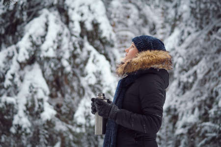 walks outdoors: girl drink hot tea from a thermosの写真素材
