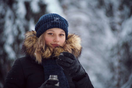 walks outdoors: girl drink hot tea from a thermosの写真素材