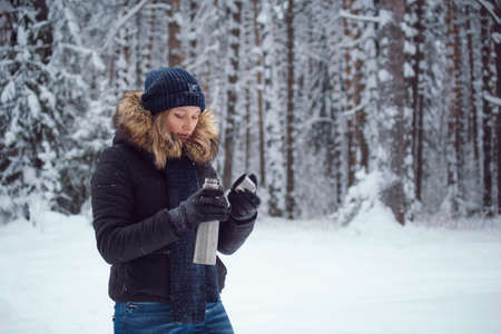 walks outdoors: girl drink hot tea from a thermosの写真素材