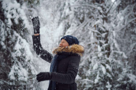 Happy young woman playing with snow, winterの写真素材