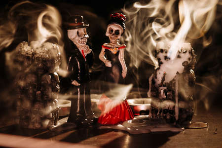 Halloween: smoke from extinct candles has filled space and has shrouded figures of the man and the woman in the uniform of skeletonsの写真素材