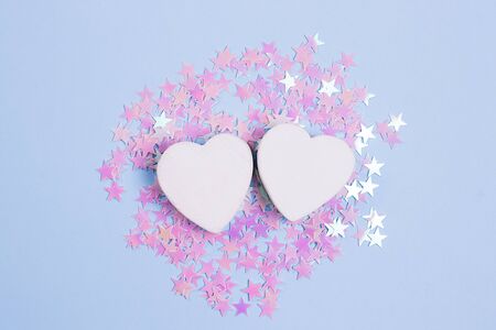 Two white heart on pastel blue background with scattered pink glitter stars. Love concept for your design.の写真素材