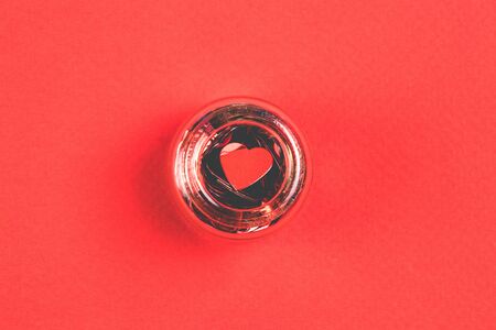 Confetti in the form of heart on the top of decorative bottle on a red background. Valentine's Day concept.の写真素材