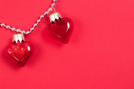 A couple of beautiful decorative red glass hearts with reflects on red background. Valentines Day Concept. Place for your text.の写真素材