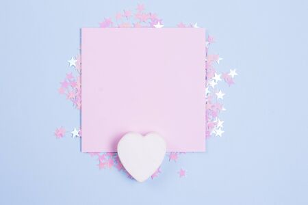 White wooden heart and pastel pink blank card mockup on pastel blue background with scattered pink glitter stars. Place for your text.の写真素材