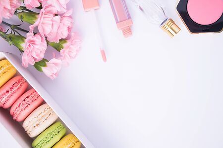 Colorful macaroons, perfume, blush, lipstick and pink carnation flowers on a white background. Isolated. Spring`s consept.の写真素材