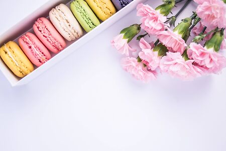 Beautiful colorful macaroons and pink carnation flowers on a white background. Isolated.の写真素材