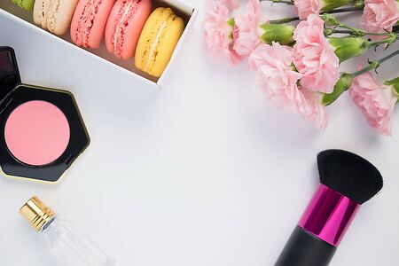 Beautiful colorful macaroons, perfume, blush, brush and pink carnation flowers on a white background. Isolated.の写真素材