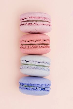 A beautiful vertical row of macaroons on the peach color background. Trendy dessert.の写真素材