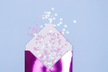 Beautiful shiny envelope with glitter confetti in a form stars on a blue background. Festive concept.の写真素材
