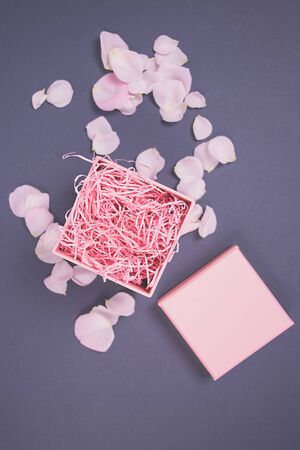 Beautiful rose petals on pink box on a dark background. Flat lay.の写真素材
