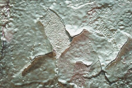 Fragment of an old wall with silver paint. Stucco texture`s background. Peeling of silver paint....