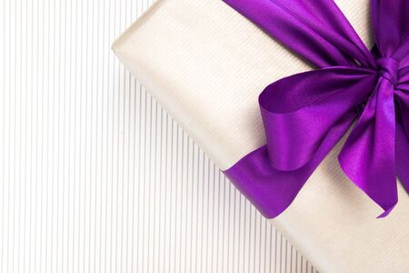 Gift with violet ribbon and bow-knot on light background. Copy space.の写真素材