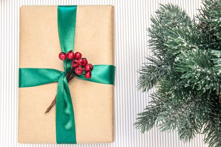 Gift in craft paper with green ribbon, red berries, branches of spruce on a white background.の写真素材