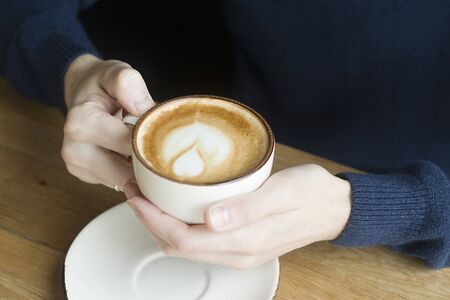 A cup of coffee with milk in the hands. Morning time.の写真素材