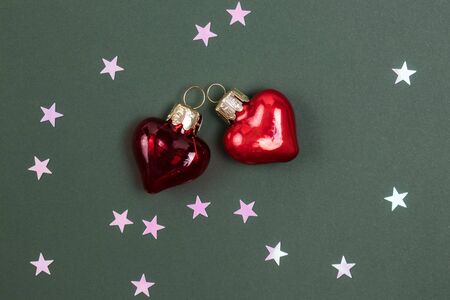 Beautiful red glass hearts on green background with pink stars confetti. Top view. Valentines Day Concept.の写真素材