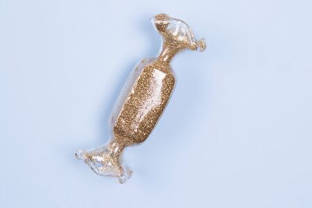 Toy in the shape of holidays candy with the gold glitter on a pastel blue background.の写真素材