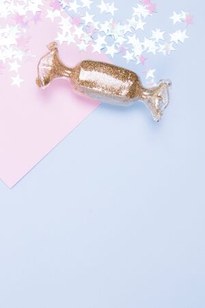 Toy in the shape of holidays candy with the gold glitter and glitter stars. Pastel blue and pink backgeound.の写真素材