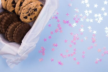 Homemade tasty cookies in a white box on a pastel blue background with pink stars confetti.の写真素材