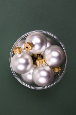 Many matte white christmas balls in a round box on a green background. Christmas and New Year concept.の写真素材