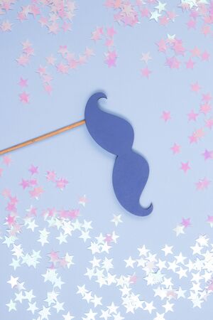 Holiday blue fake mustache and pink sprinkling stars on a pastel blue background. Flat lay background.の写真素材