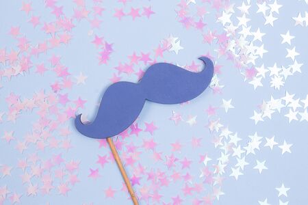 Blue fake mustache on a blue background with glitter stars. Holidays time.の写真素材