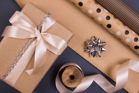 Holidays gift box in a craft cover, design holidays paper, beige atlas ribbon, toy in the shape of holidays candy, silver bow.の写真素材